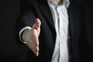 Businessman extending hand for a handshake, symbolizing a sales interaction built on trust and mutual agreement.